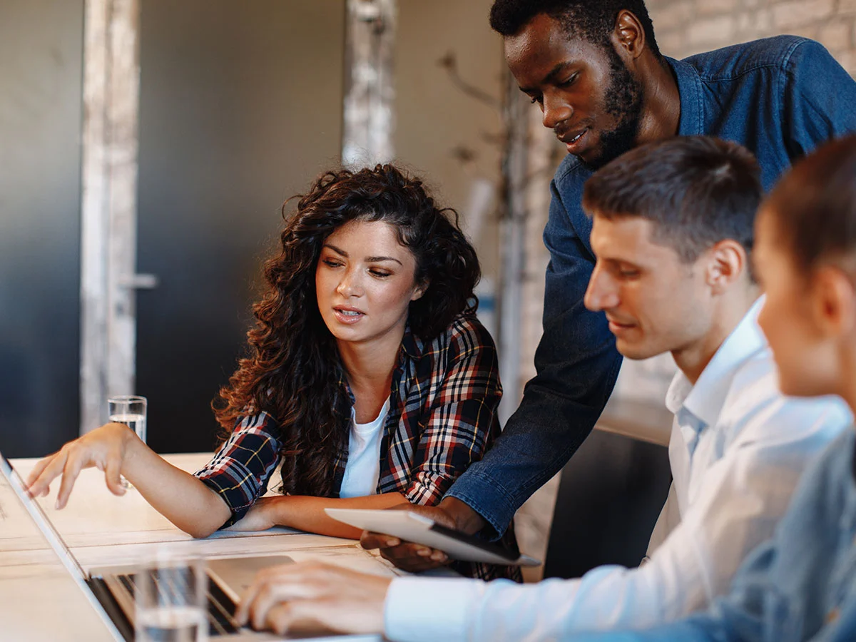 AdobeStock_173672782-crop.webp A diverse group of individuals collaborating around a laptop, engaged in discussion and teamwork.